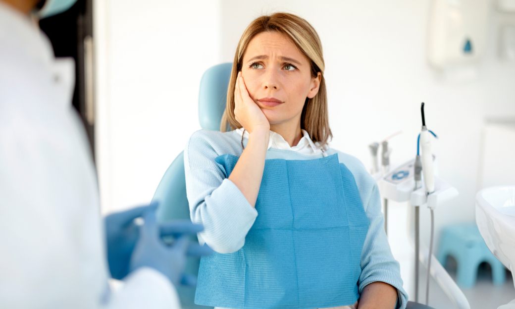 Personne dans un cabinet de dentiste qui se tient la machoire
